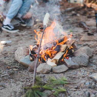 a girl roasting bannock over a fire