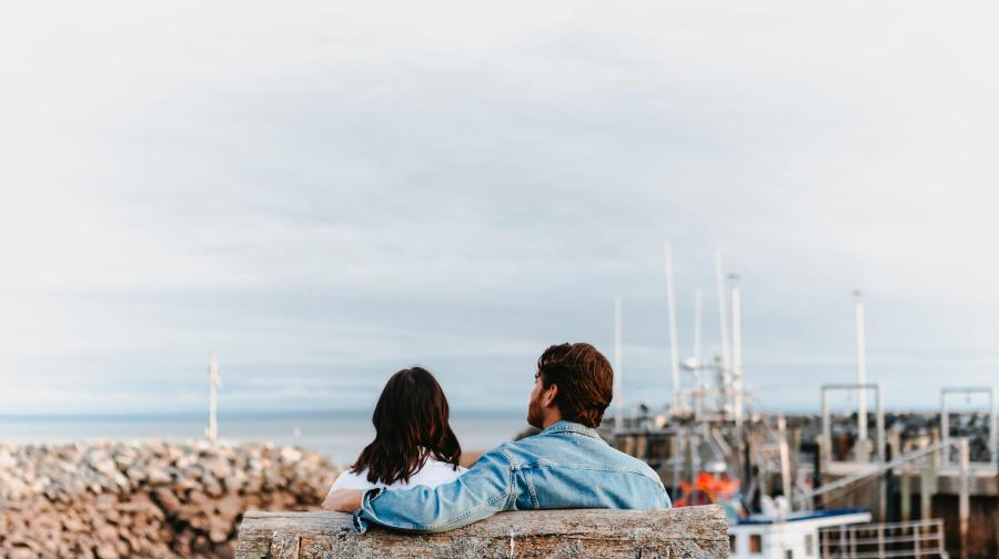two people sitting on a bench at the docks